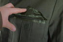 Close-up of hand opening chest pocket of genuine Greek Army gabardine wool Ike jacket in olive blaze color
