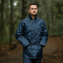 Man wearing original British RAF waterproof blue parka raincoat standing outdoors in forest setting