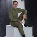 Man wearing genuine Czech army M85 liner thermal trousers and green long-sleeve top sitting on white block