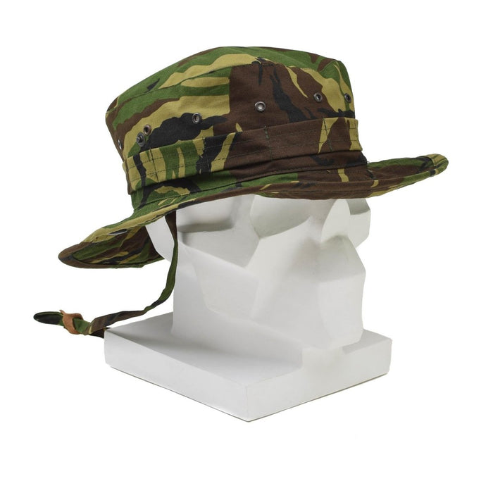 Echte Nederlandse militaire booniehoed met DPM-camouflage, brede rand, nekflap en verstelbare kinband op het hoofd van een witte mannequin.