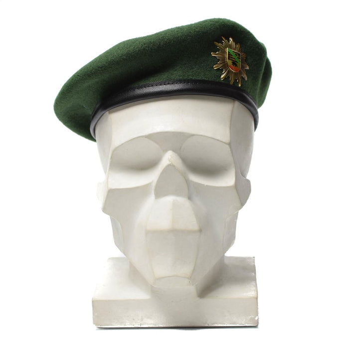 Groene barethoed van Duitse politiewol met metalen kokarde-insignes op het hoofd van de witte mannequin