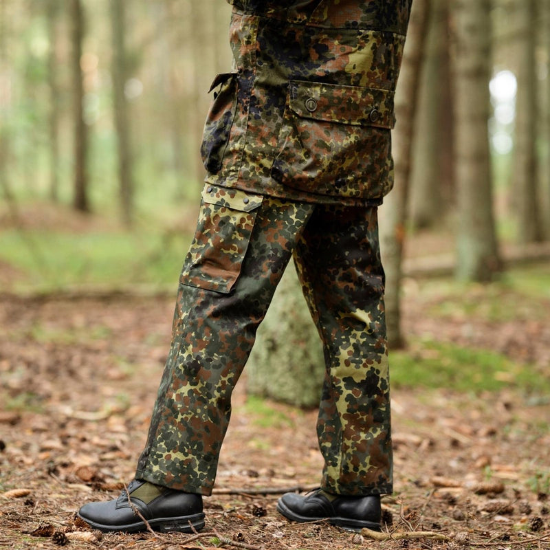 German Military style field cargo pants in flecktarn camo with multiple pockets and durable fabric in forest setting.