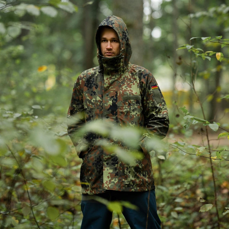 Man wearing Mil-Tec German army GoreTex Flecktarn camo waterproof rain jacket in forest setting