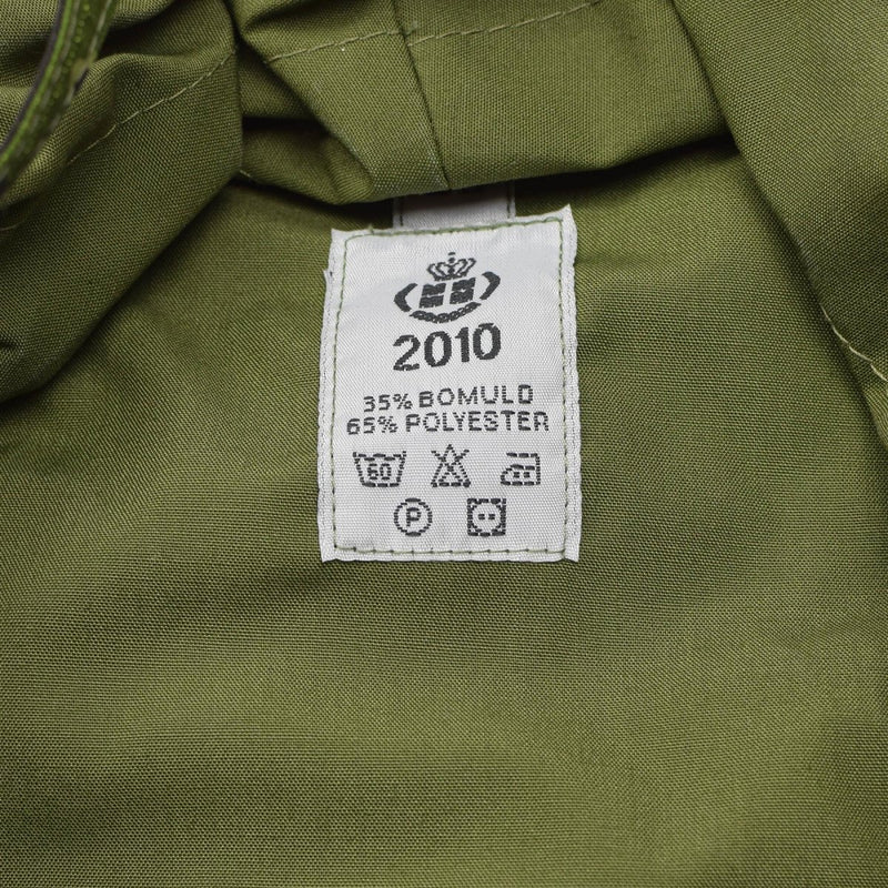 Close-up of green fabric label showing 2010, 35% bomuld 65% polyester, and care symbols on Danish M84 bucket hat