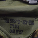Close-up of label with NSN and production codes inside a green military-style shoulder bag pouch