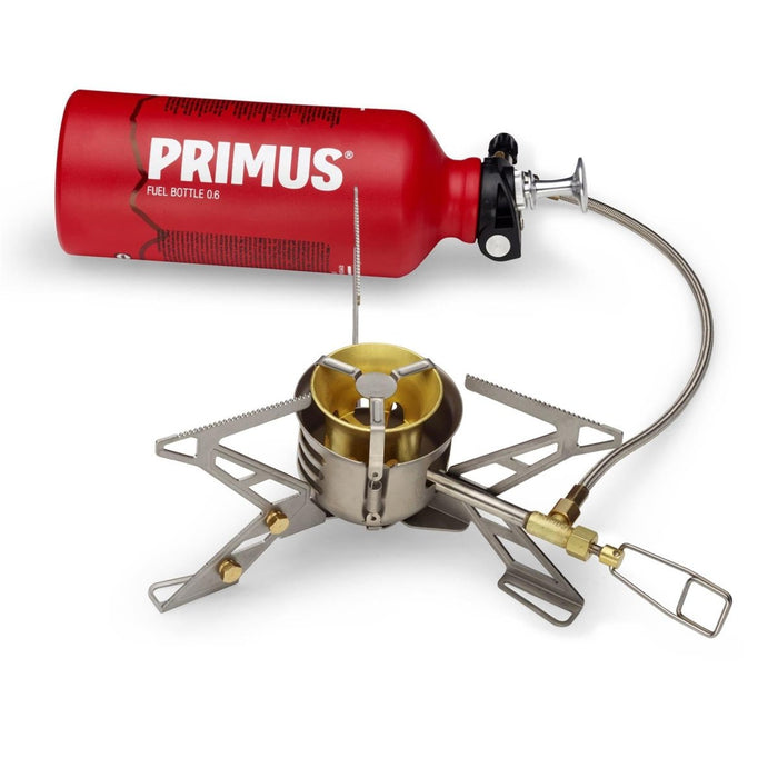 Primus OmniFuel II multifuel kampeerkooktoestel met rode brandstoffles, roestvrijstalen steunen en brandstofslang voor buitenkoken.